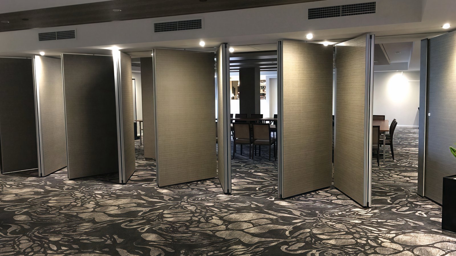 Folding operable partitions stacked open along a hotel conference corridor